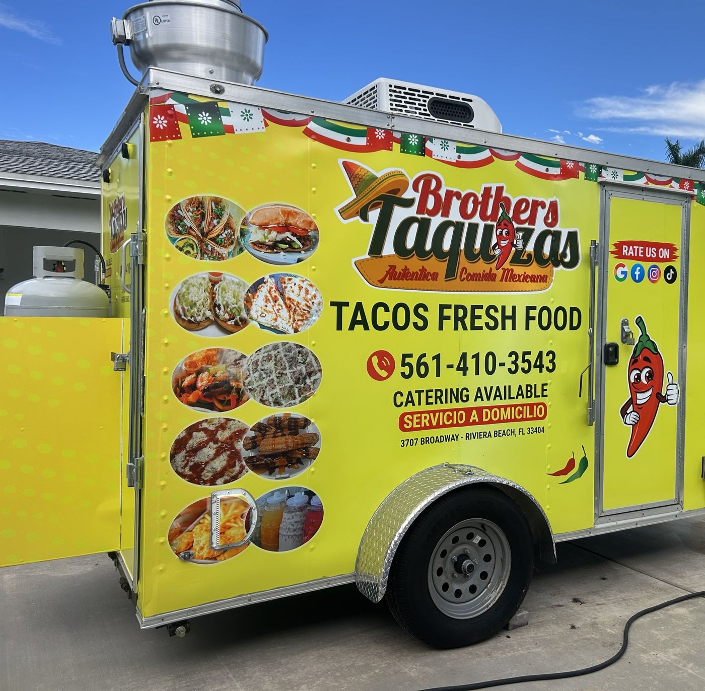 The yellow Brothers Taquizas catering trailer with its menu wrap, ready to cook at an event